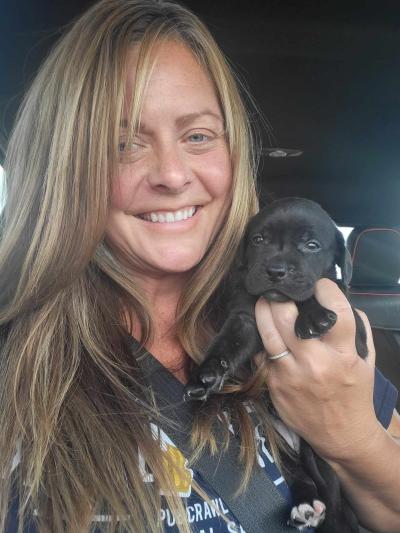 Courtney Butler holding a black puppy